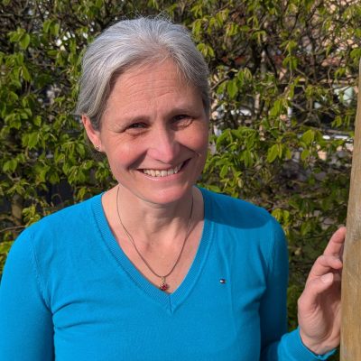 Diana lächelnd an einem Balken stehend