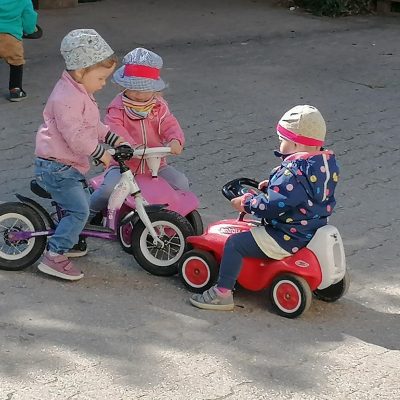 3 Little Munchkins fahren Bobbycar im Hof