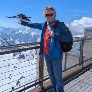 Tagespapa Swen steht auf einem Berg mit ausgestrecktem Arm auf dem ein Vogel gelandet ist.